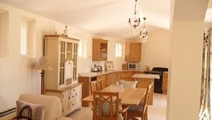 A spacious living area with a wooden dining table and chairs, a sofa, and a kitchen in the background. - Superb Villa with Private Pool and Sea Views (Sainte-Maxime)