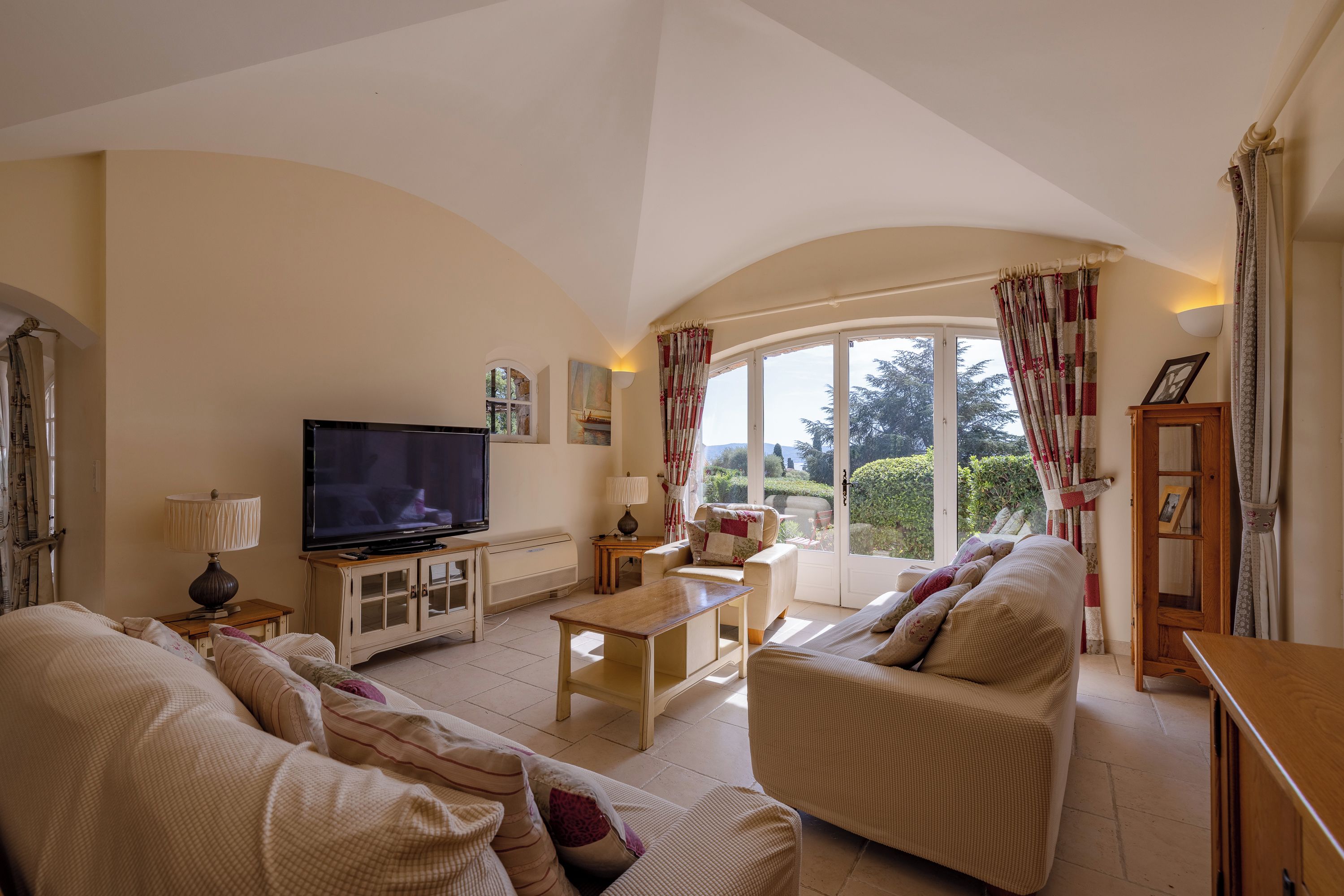 A living room with a television, sofa, and a large window with curtains.