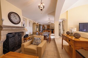 A spacious living room with a fireplace, a dining area, and a kitchen in the background. - Superb Villa with Private Pool and Sea Views (Sainte-Maxime)