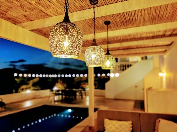 Ein Poolbereich mit hängenden Lichtern und einer Holzbeschichtung.