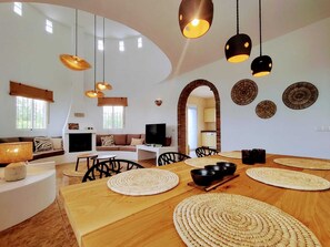 Ein modernes Wohnzimmer mit einem Holzesstisch, gewebten Untersetzern und einem Fernseher.