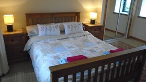Una cama bien hecha con ropa de cama floral, dos lámparas de noche y un cabecero de madera.