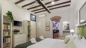 Ein Hotelzimmer mit einem großen Bett, einem Fernseher, einem Bücherregal und einem Schreibtisch.