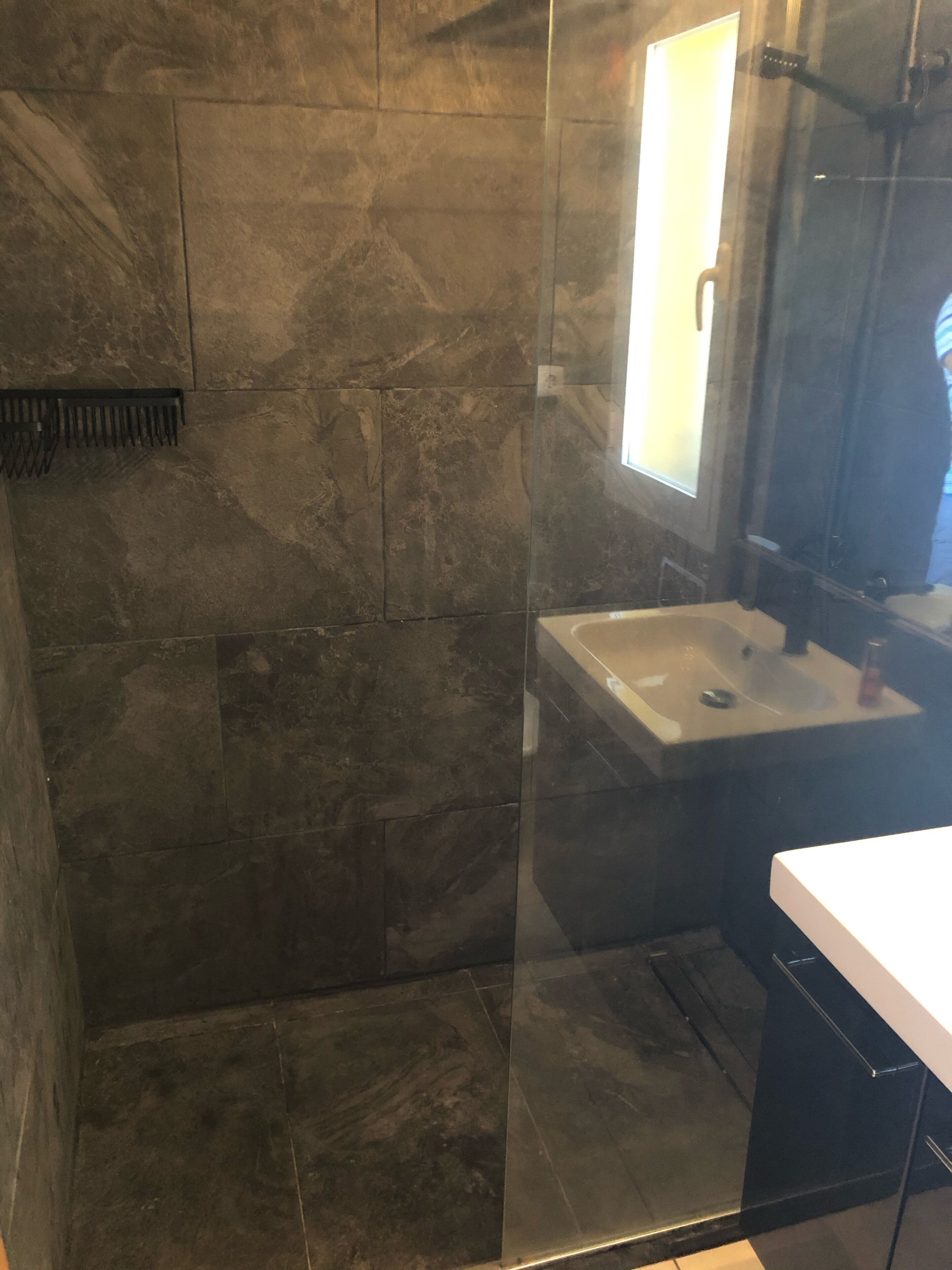 Une salle de bain moderne avec une douche à parois de verre, un lavabo blanc et un miroir.