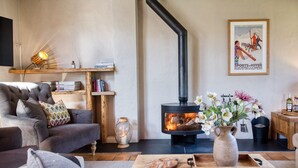A cozy living room with a fireplace, a sofa, a coffee table, and a bookshelf.