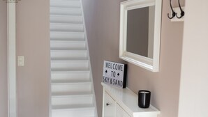 Un escalier menant à une pièce où est affiché un panneau indiquant : « BIENVENUE À SKY & SAND ».
