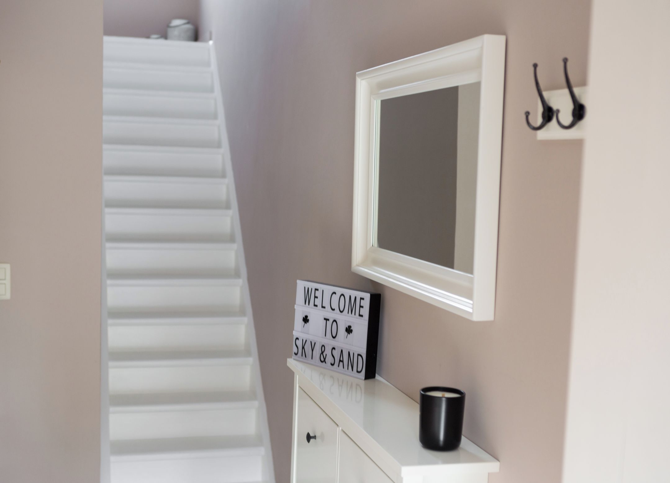 A staircase leading to a room with a sign reading "WELCOME TO SKY & SAND".