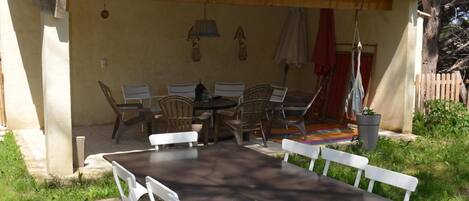 An outdoor patio with a table and chairs, surrounded by trees and a wooden fence.
