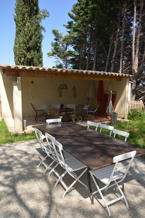 Une terrasse extérieure avec une table et des chaises, entourée d’arbres et d’une clôture en bois.