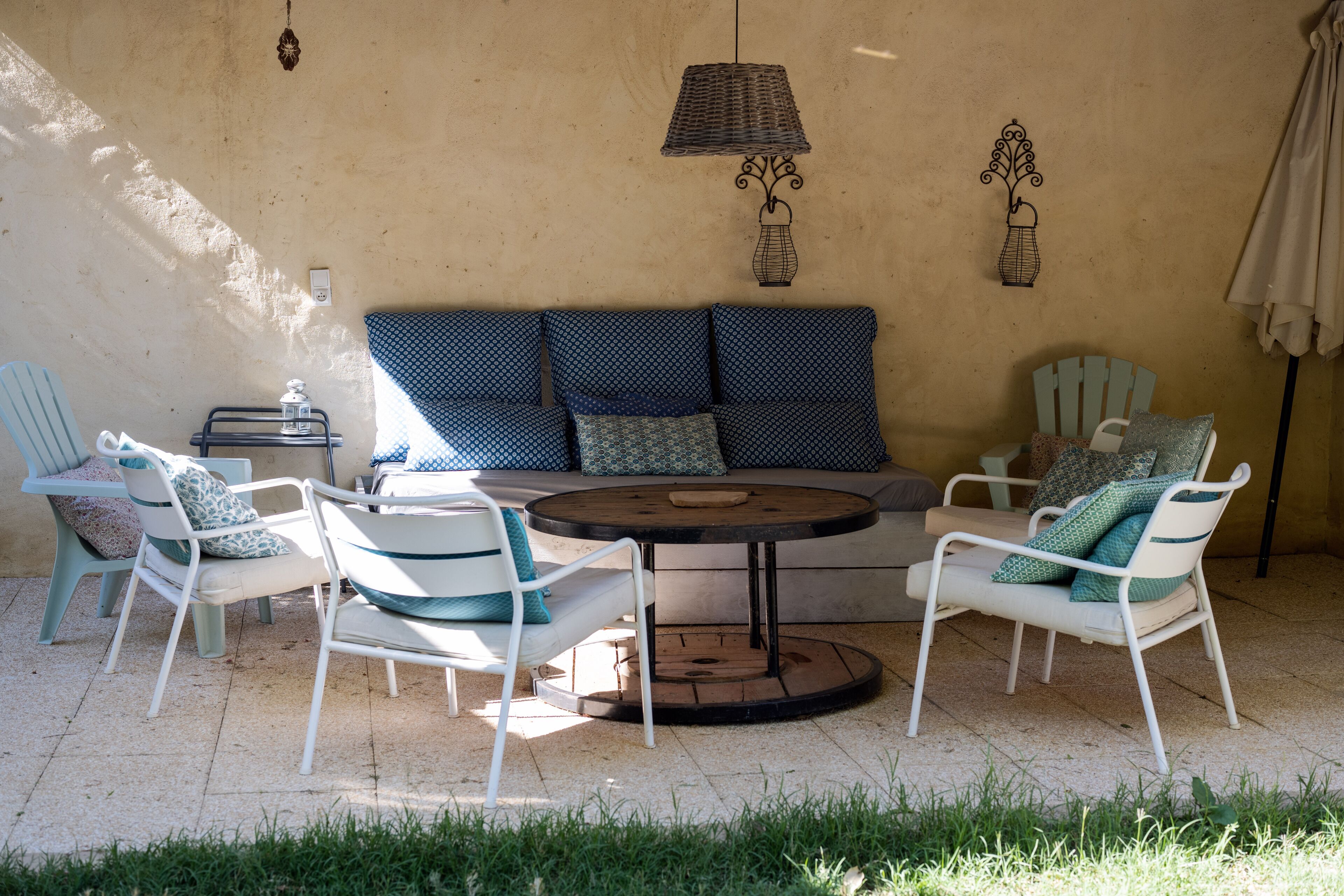 A patio with a round table, white chairs, and blue patterned cushions.