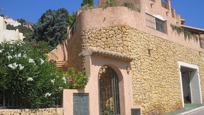 A building with a stone facade, a central arched entrance, and a balcony with metal railings.