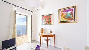 Enjoy a sea view from the large window in this stylish living room, featuring a flat-screen TV and two vibrant paintings.