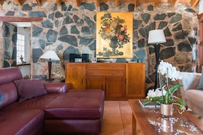 A stone wall interior with a sofa, a coffee table, and a cabinet.
