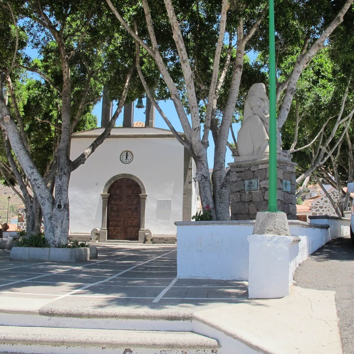 Un bâtiment doté d’une horloge, d’une statue et d’une zone pavée agrémentée d’arbres.