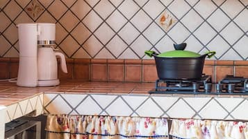 Una cocina con estufa a gas, cafetera y una olla sobre la hornilla.