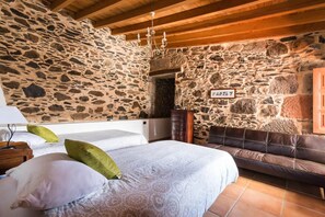 A bedroom with a stone wall, a bed with pillows, a wooden ceiling, and a sign on the wall.