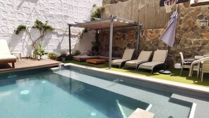 Piscina com espreguiçadeiras e área de estar coberta.