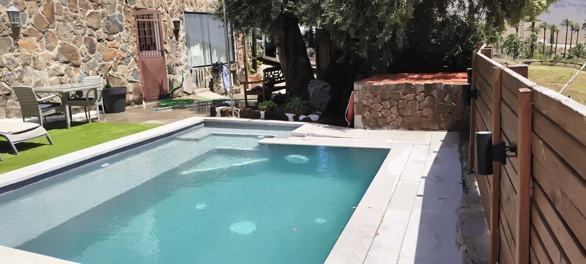 Ein rechteckiger Pool mit Steinmauer und Holzzaun.