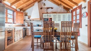 Uma cozinha com armários de madeira, uma mesa de jantar com cadeiras e um lustre.