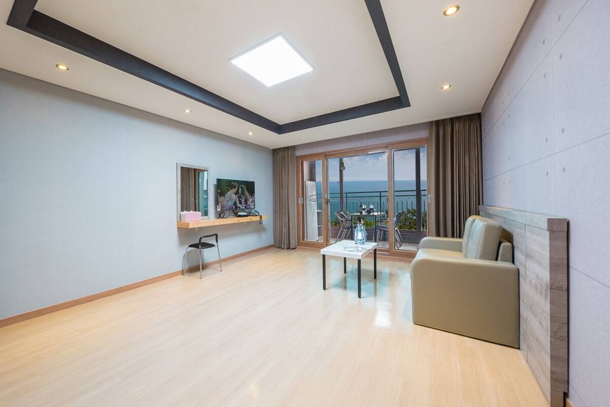 A spacious living room with a large window, a sofa, a coffee table, and a TV.