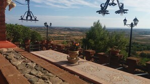 Eine Terrasse mit Fliesenboden, Blumentöpfen und Blick ins Grüne.