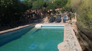 A clear swimming pool with a tiled edge, surrounded by stone walls and potted plants. - Sardinia Panoramic Villa oasis relax private swimming pool. LAST MINUTE May-June (Maracalagonis)