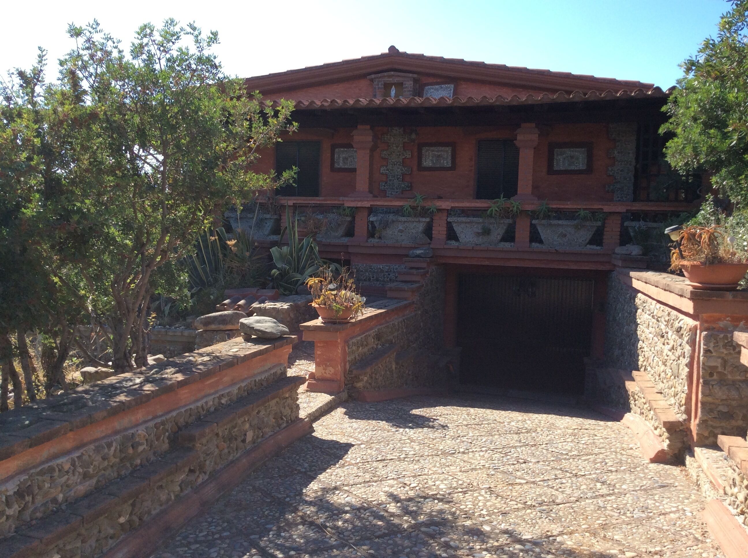 Un edificio tradicional con techo de tejas, escalones de piedra y plantas en macetas.