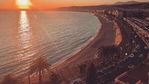 A coastal cityscape at sunset with a beach, roads, and buildings. - STUNNING BEACHFRONT APARTMENT ON PROMENADE,  ENDLESS SEAVIEWS, SUPERB LOCATION  (Nice)