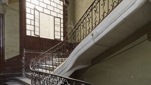 A spiral staircase with ornate metal railings and a wooden door at the top.