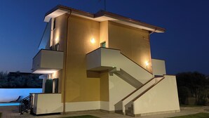 Um edifício moderno com telhado plano, escadaria e área de piscina.