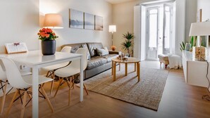 Ein modernes Wohnzimmer mit einem weißen Sofa, einem Esstisch mit Stühlen, einem Couchtisch und einem großen Fenster mit Blick.