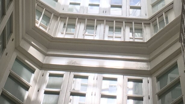Ein mehrgeschossiges Atrium mit Oberlichter, mit mehreren Balkonen und Fenstern.