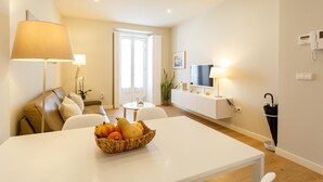 Ein modernes Wohnzimmer mit Esstisch, Sofa, Fernseher und Lampe.