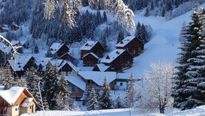 A snow-covered mountain village with wooden chalets and a ski slope.