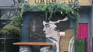 A storefront with a mural of a woman's face, a sign reading "Casa Tua", and two barrels with text. - Homely - in the heart of Camden (London)