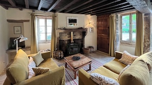 A cozy living room with a fireplace, wooden beams, and comfortable seating. - Cottage and private garden - rural bliss for two (or 4 with mezzanine) (Corsaint)