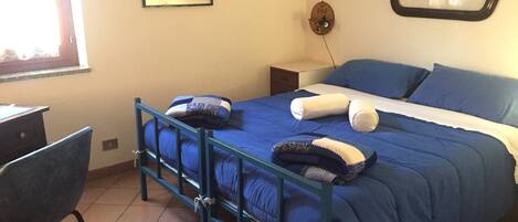 Une chambre à coucher avec un lit, une chaise, un bureau, une carte accrochée au mur et une fenêtre.
