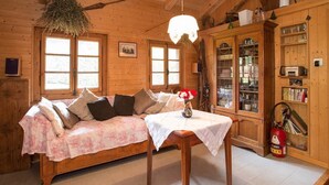 L’intérieur d’un chalet en bois accueillant, avec un canapé, une table ornée d’un vase et un meuble avec des portes en verre.