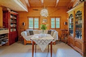 Un intérieur en bois comprenant une table à manger, des chaises, un lustre et des meubles de rangement en bois.