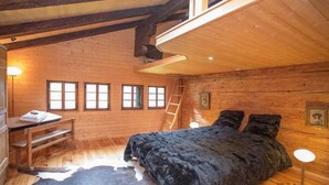 Une chambre confortable dans un chalet en rondins, avec un lit, un bureau et une échelle.