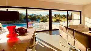 A modern living room with a large window overlooking a pool and garden.