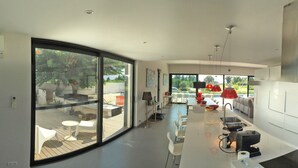 A modern kitchen with a central island, stainless steel appliances, and a large sliding glass door leading to an outdoor patio area.