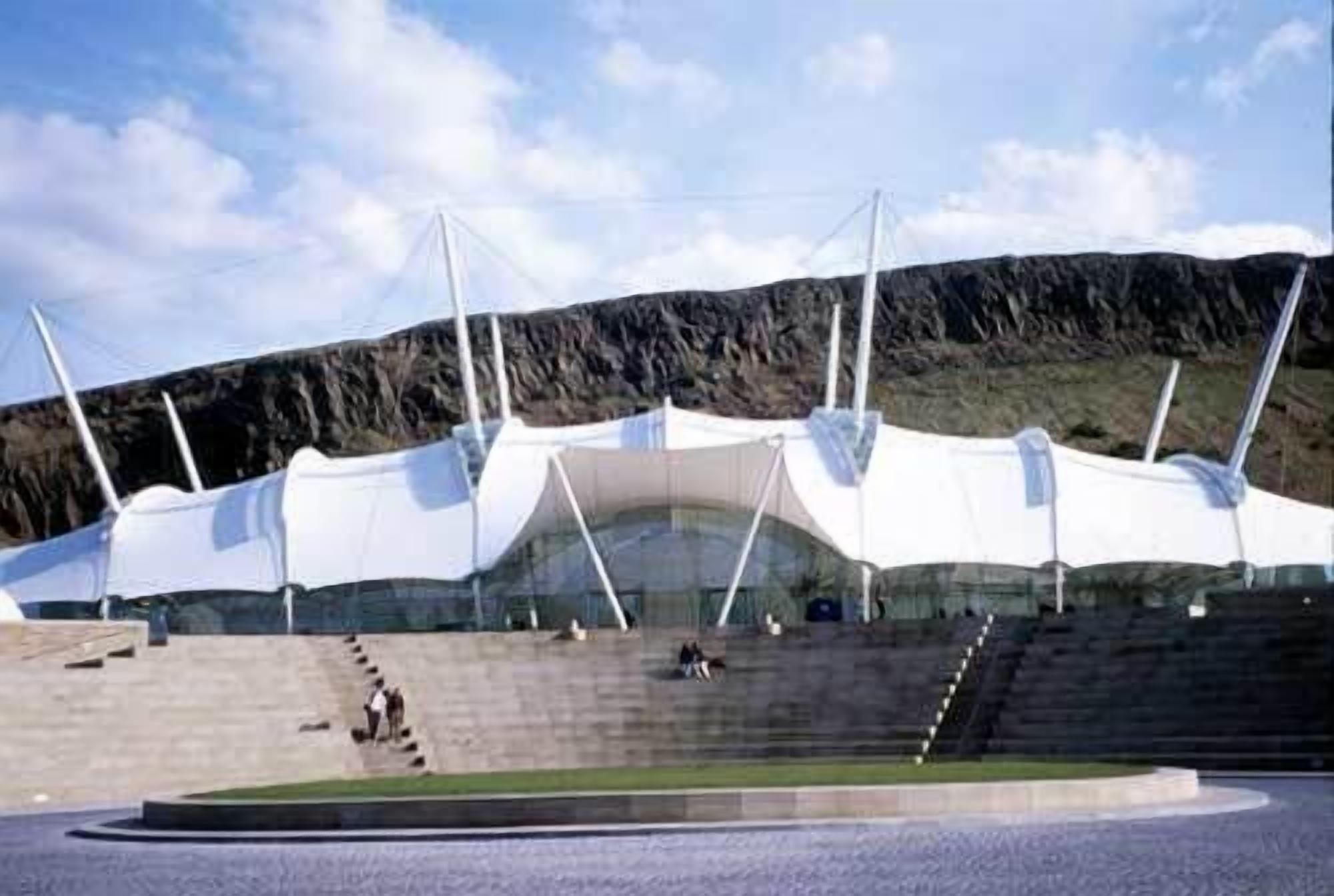 A stadium with tiered seating and a large open field in front.