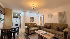 Ein gemütliches Wohnzimmer mit einem Holztisch, zwei Sofas und einem Essbereich mit Tisch und Stühlen.