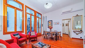 Un vaste salon doté de grandes fenêtres, un coin repas et un couloir menant à une salle de bain.