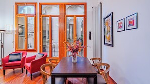 Un coin repas avec une table en bois, des chaises rouges et un vase de fleurs.