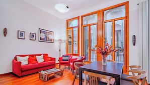 Un salon moderne avec un canapé rouge, une table à manger en bois et une grande fenêtre donnant sur la ville.