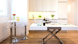 Una cocina moderna con una mesa para dos personas, una botella de vino y un frutero.