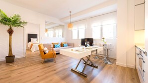 Una sala de estar moderna con una mesa de comedor, sofá y una planta grande en maceta.