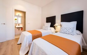 Een hotelkamer met twee bedden, een badkamer met spiegel en een nachtkastje met lamp.